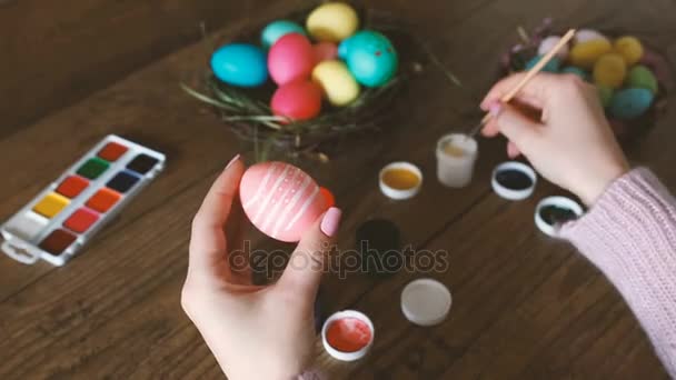 Manos femeninas pintando huevos de Pascua en mesa de madera oscura. Enfoque selectivo . — Vídeos de Stock