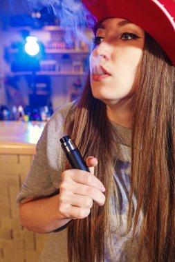 Genç kadın kırmızı bere duman elektronik sigara vape dükkanında güzel.