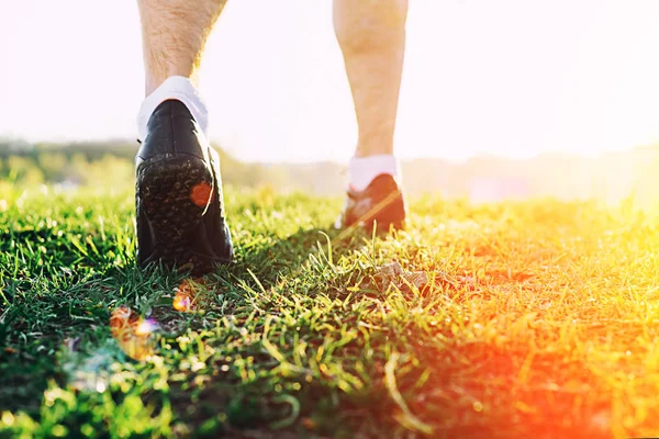 young athlete feet running in park closeup on shoe. Male fitness athlete jogger workout in wellness concept at sunset. Sports healthy lifestyle concept.