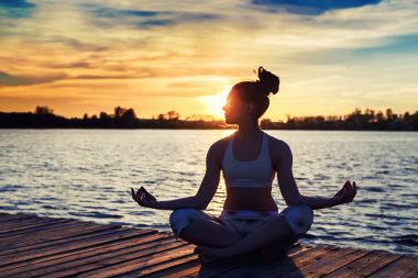 Genç kadının gün batımında yoga egzersizleri Gölü sahilde yapması