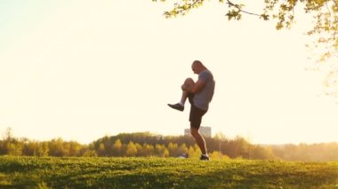 parkta egzersiz için hazırlanıyor germe egzersiz yaparak genç atletik atlet. gün batımı, tonda video