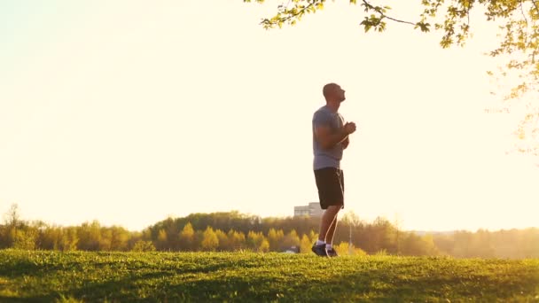 Joven atleta haciendo ejercicio de estiramiento, preparándose para el entrenamiento en el parque. puesta de sol, tonificado vídeo — Vídeos de Stock