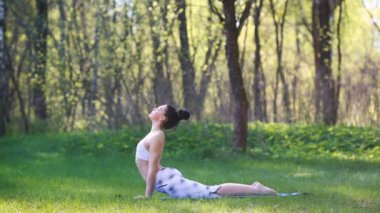 Genç kadın yaz Şehir Parkı yoga egzersizleri yapıyor. Sağlık yaşam tarzı kavramı.