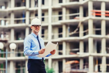 Handsom inşaat mühendisi inşaat sahasında kameraya bakıyor