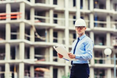 Handsom inşaat mühendisi inşaat sahasında kameraya bakıyor