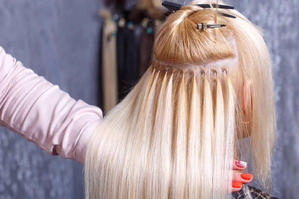 Haarverlängerungen. Friseur macht Haarverlängerungen für junges Mädchen, Blondine in Schönheitssalon. Selektiver Fokus. — Stockfoto