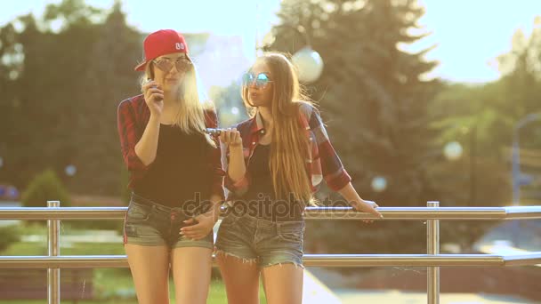 Two women vaping outdoor. The evening sunset over the city. Toned image. — Stock Video