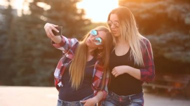 Selfie fotoğraf Smartphone'da yapmak mutlu iki gülümseyen kız portresi. kentsel arka plan. Akşam güneşin şehri.