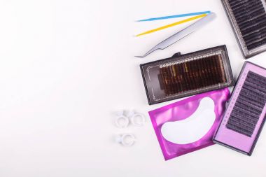 Beyaz arkaplanda kirpik uzatma araçları. Kirpik uzatma için aksesuarlar. Yapay kirpikleri. Üst görünüm.