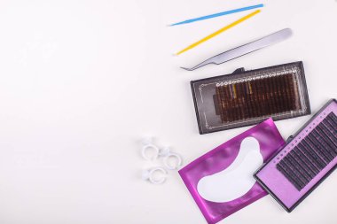 Beyaz arkaplanda kirpik uzatma araçları. Kirpik uzatma için aksesuarlar. Yapay kirpikleri. Üst görünüm.