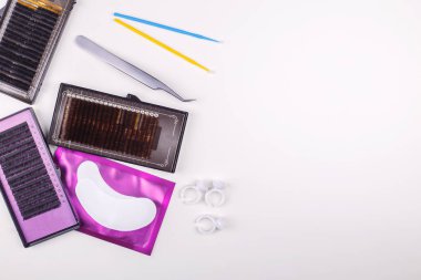 Beyaz arkaplanda kirpik uzatma araçları. Kirpik uzatma için aksesuarlar. Yapay kirpikleri. Üst görünüm.