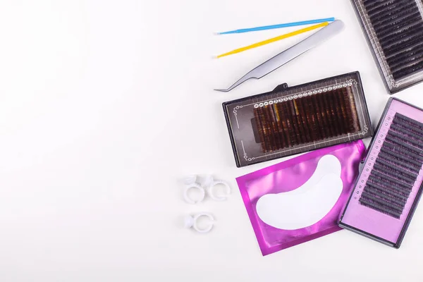 Beyaz arkaplanda kirpik uzatma araçları. Kirpik uzatma için aksesuarlar. Yapay kirpikleri. Üst görünüm.