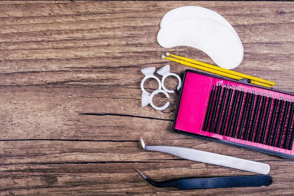 Kirpik uzatma araçlar ahşap arka plan üzerinde. Kirpik uzantıları için aksesuarlar. Suni kirpikler. Üstten Görünüm.