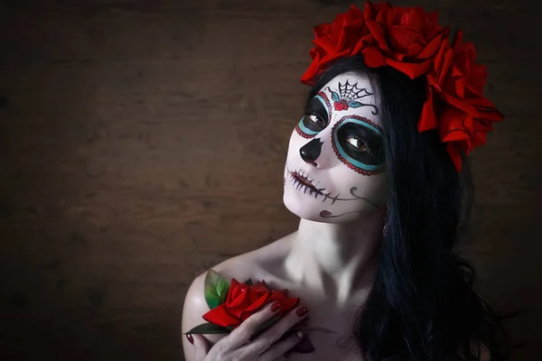Dag van de doden. Halloween. Jonge vrouw in dag van de dode masker schedel gezicht kunst en rose. Donkere achtergrond. — Stockfoto