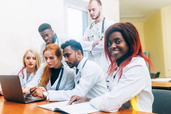 Equipe multirracial de jovens médicos que trabalham no computador portátil no consultório médico . — Fotografia de Stock