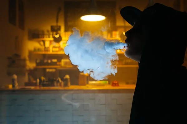 Silhouette de Vaping girl. La jeune hipster vape e-cig au vapeshop. Style hip-hop. Gros plan . — Photo