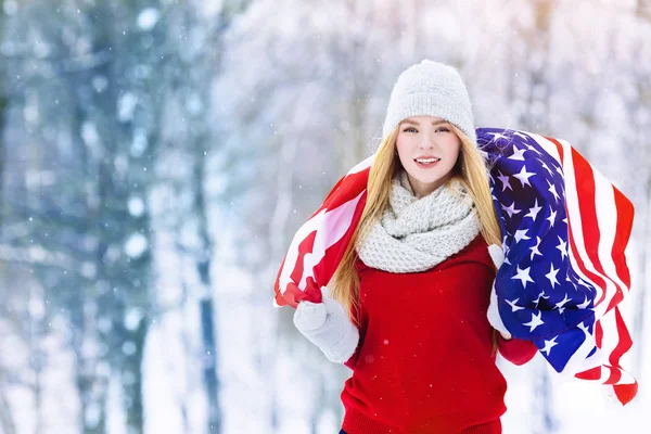Retrato de invierno de una joven adolescente con bandera de Estados Unidos. Belleza Joyful Model Girl riendo y divirtiéndose en el parque de invierno. Hermosa joven al aire libre. Disfrutando de la naturaleza, el invierno — Foto de Stock