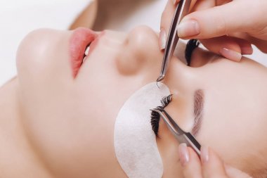 Kirpik uzatma prosedürü. Uzun kirpikli kadın gözü. Yaklaş, seçici odaklanma.