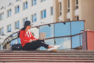 Dizüstü outdors üzerinde çalışan mutlu hipster genç kadın. Üniversite kampüsü içinde dizüstü bilgisayar kullanan öğrenci kız. Tonlu görüntü.