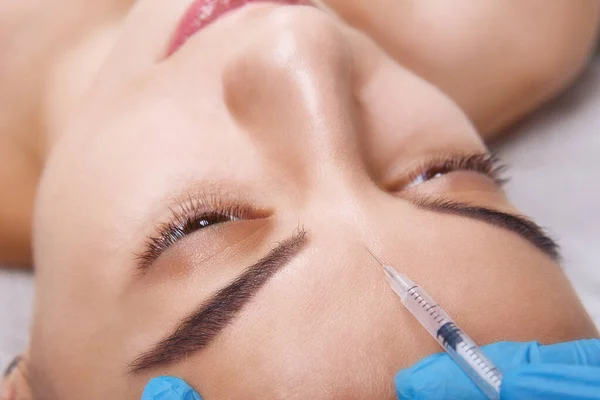 Nahaufnahme Porträt einer jungen kaukasischen Frau, die eine kosmetische Botox-Injektion in die Stirn bekommt. Menschen, Kosmetologie, plastische Chirurgie und Schönheitskonzept. — Stockfoto