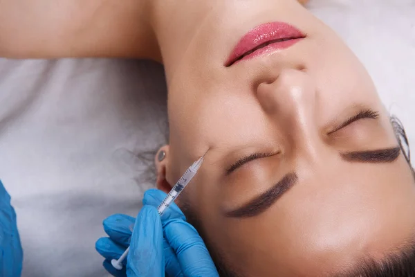 Yüz Güzelliği Enjeksiyonları. Portre Güzel Genç Kadın Hyaluronic Asit Enjeksiyonu alıyor. Eldivenli Ellerin Yakın Çekici Kadın Yüzü Şırıngası Tutuşu.