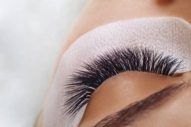 Kirpik uzatma yordamı. Kadın uzun mavi kirpik gözle. Ombre etkisi. Yakın, seçici odak.