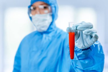 Tehlikeli madde koruma giysisi içindeki sıhhiye, Çin, Wuhan 'dan alınan koronavirüs pozitif kan örneğinin bulunduğu bir test tüpü tutuyor. 2019 ncov salgını. Coronavirüs 'ü durdurun. Mers.