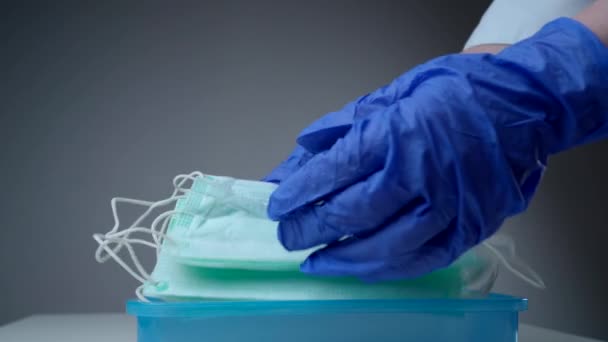 Врач или медсестра берут респираторную маску из пластикового контейнера. Руки защищены медицинскими перчатками. Коронавирус, COVID-19, атипичная пневмония, грипп, заболевания, передающиеся по воздуху . — стоковое видео