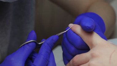 Güzellik salonundaki profesyonel kadın manikür ustasının yaklaşım süreci tırnaklarının kenarındaki kuru deriyi söküp makasla kesiyor. Vücut bakımı kavramı. Güzellik uzmanı dosyasının bir müşteriye çivileri