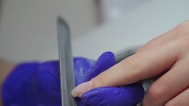 Frau in einem Salon, die von einer Kosmetikerin mit Nagelfeile gepflegt wird. Frau erhält Nagelmaniküre. Kosmetikerin feilt Nägel an Kunden. Maniküre im Schönheitssalon. — Stockvideo