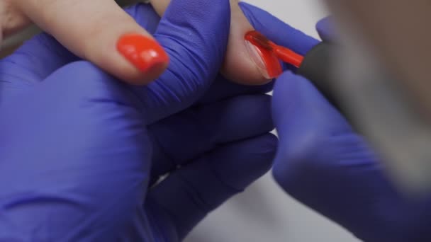 Close-up van professionele schoonheidsspecialiste manicure master polish nagel. Een vrouw die nagelmanicure krijgt. Bedek de nagels met rode vernis. Nagel manicure proces in een schoonheidssalon. — Stockvideo