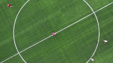 Futbol sahasının havadan aşağı görüntüsü. Oyunun başlangıcı. Dışarıda futbol oynayan iki takım. Baş üstü..