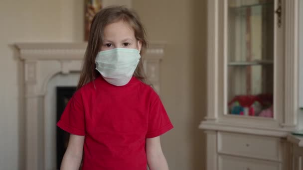 Fique em casa conceito. Menina pequena em máscara segurando sinal dizendo ficar em casa para proteção do vírus e cuidar de sua saúde de COVID-19 . — Vídeo de Stock