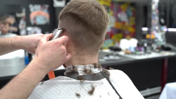 Чоловічі стрижки з електричною бритвою. Підстригайте волосся, підстригаючи волосся. Барбер робить зачіску для клієнта в перукарні за допомогою перукаря. Людина пердить з електричною трубкою. Стріляй повільніше. — стокове відео