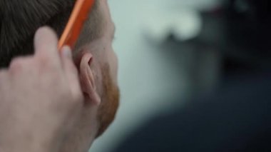 Elektrikli traşlı erkek saç kesimi. Saç kesme stilini kapat. Berber, berber dükkanında saç kesme makinesi kullanarak müşterisinin saçını kesiyor. Elektrikli traşlı erkek kuaförü. El kamerasıyla. 4K.