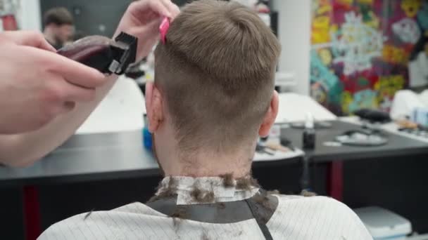 Manlig frisyr med elektrisk rakkniv. Närbild av hår trimmer frisyr. Frisören klipper frisyren i frisörsalongen med hjälp av hårklippare. Man frisör med elektrisk rakapparat. Handhållen skott. 4K. — Stockvideo