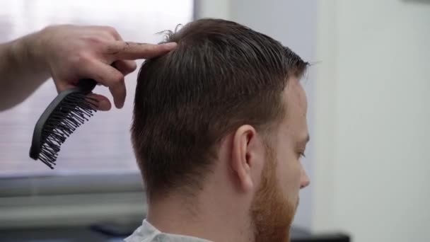 Barber suší mužské vlasy v kadeřnickém salónu. Ruční střelba. 4K. — Stock video