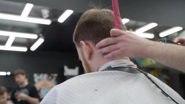 男性用电动剃须刀理发。剪短头发的特写镜头.理发师在理发店用理发为顾客理发.男人用电动剃须刀理发.手持射击。4K. — 图库视频影像