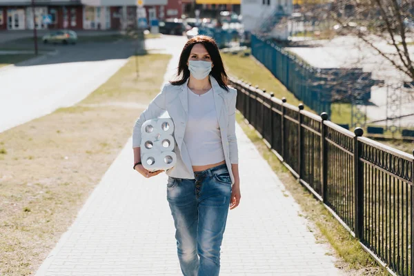 Woman walking in medical mask with toilet paper during coronavirus outbreak or covid-19. concept of covid-2019 quarantine. dangerous COVID virus, people panic — Stock Photo, Image