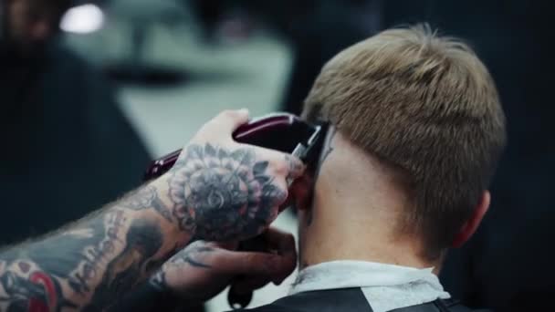 Manlig frisyr med elektrisk rakkniv. Närbild av hår trimmer frisyr. Frisören klipper frisyren i frisörsalongen med hjälp av hårklippare. Man frisör med elektrisk rakapparat. Handhållen skott. 4K. — Stockvideo