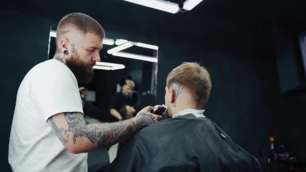 理髪店でシェービングマシンと理髪師のトリミング。ヘアスタイリングプロセス。髭を生やした男の髭を切るヘアスタイリストのクローズアップ. — ストック動画
