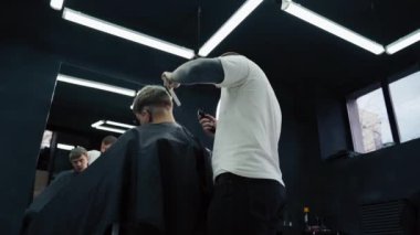 Elektrikli traşlı erkek saç kesimi. Saç kesme stilini kapat. Berber, berber dükkanında saç kesme makinesi kullanarak müşterisinin saçını kesiyor. Elektrikli traşlı erkek kuaförü. El kamerasıyla. 4K.