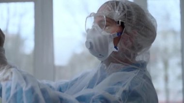 Koruyucu giysili doktor klinikteki Covid-19 hastasının röntgenini inceledi. Coronavirüs salgını konsepti