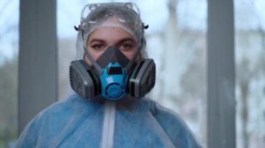 Coronavirus salgını sırasında koruyucu kıyafet giyen kadın portresi. Tehlikeli takım elbiseli kadın doktor, solunum maskesi, eldivenler ve gözlükler klinikte ya da hastanede çalışma gününe hazırlanıyor.