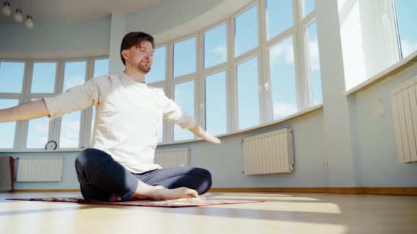 De mens beoefent yoga. Jonge aantrekkelijke man die ademhalingsoefeningen doet. Een man die thuis mediteerde tijdens de pandemie. Ontspannings- en rustconcept voor isolatie. — Stockvideo