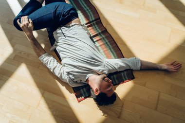 Adam yoga yapıyor. Genç ve çekici erkek nefes egzersizleri yapıyor. Adam salgın sırasında evde meditasyon yapıyormuş. İzolasyon için dinlenme ve dinlenme konsepti. Kaydırma atışı.
