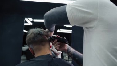 Elektrikli traşlı erkek saç kesimi. Saç kesme stilini kapat. Berber, berber dükkanında saç kesme makinesi kullanarak müşterisinin saçını kesiyor. Elektrikli traşlı erkek kuaförü. El kamerasıyla. 4K.