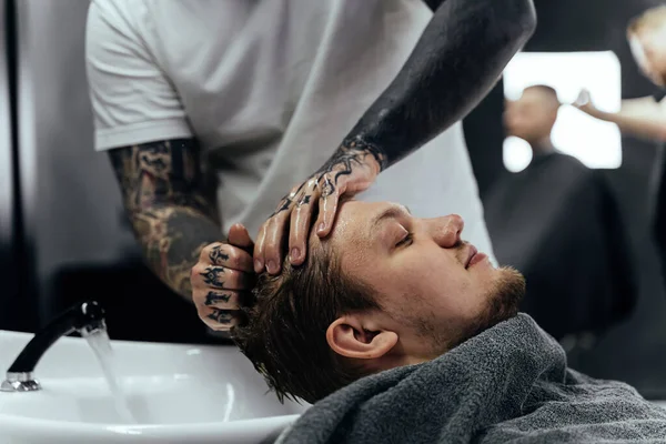 Attraktive Männer bekommen im Friseursalon einen modernen Haarschnitt. Draufsicht eines jungen Mannes, der sich in einem Friseursalon die Haare wäscht und den Kopf massiert — Stockfoto
