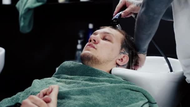 Привлекательный мужчина стрижется в парикмахерской. Вид сверху на молодого человека, который мыл волосы и мыл голову в парикмахерской — стоковое видео
