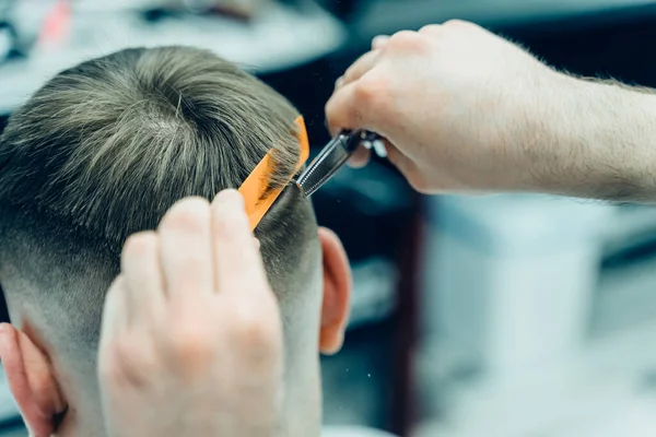 Tätowierter Barbier schneidet dem Kunden mit einer Schere die Haare. Aus nächster Nähe. Attraktive Männer bekommen im Friseursalon einen modernen Haarschnitt. Nahsicht. — Stockfoto
